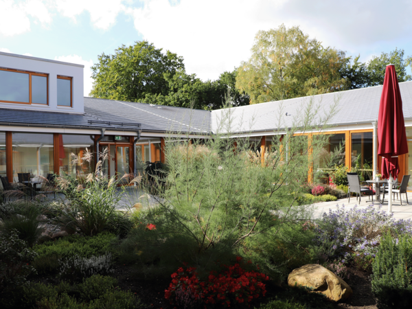 Hospizgästin in den bluehenden Hospizgarten mit Pflanzen und Terrassenmöbeln im Albertinen Hospiz Norderstedt Hospizgästin in den bluehenden Hospizgarten mit Pflanzen und Terrassenmöbeln im Albertinen Hospiz Norderstedt